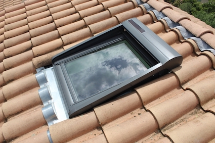 entreprise de charpente couverture zinguerie à Mâcon 71 : pose d'une fenêtre de toit de type VELUX sur une couverture tuile. Ce VELUX est installé avec un volet rouant solaire.
